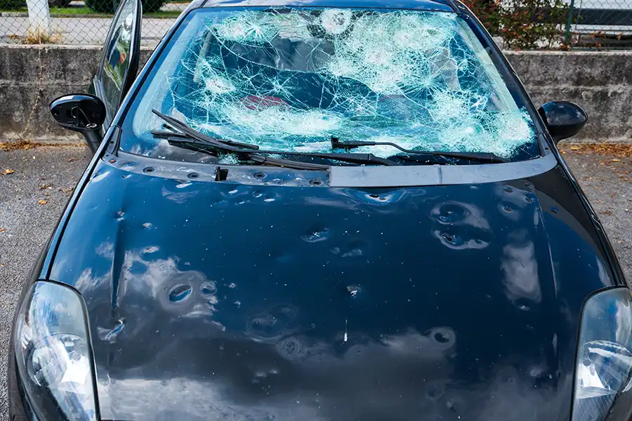 Up close image of a vehicle with the hood dented from hail damage